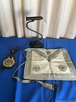 All items laid out: apron, soldering iron stand, iron, badge