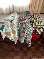 Three crocheted blankets displayed folded on a bench