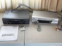 Both VHS players, manual, remotes, cable