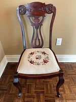 Full view of chair front, showing carving and needlepoint seat