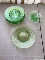 Stack of six green glass luncheon plates with swirl pattern and separate stemmed condiment dish