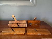 Four antique wooden molding planes on table, two with blades, two bodies only
