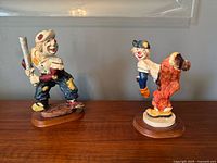 Both clown baseball figurines on wooden bases