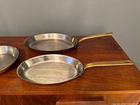 Two of the three Judge Inocuivre copper pans showing brass handles and stainless lining
