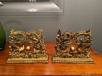 Both brass sculptures on wooden surface