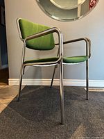 Side angle view highlighting tubular steel frame and green upholstered seat/back