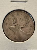 Reverse of 1951 Canadian quarter in holder showing caribou and 25 CANADA 1951