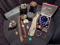 Full lot overview showing jewellery pieces, watch, box and bottle