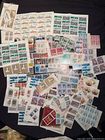 Wide view of assorted Canadian mint stamp sheets and blocks spread on surface