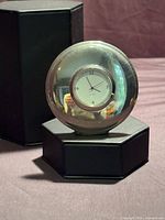 Front view of round stainless steel Holt Renfrew desk clock on stand