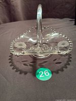 Front view of clear glass basket showing handle, beaded rim, Corn Flower etching