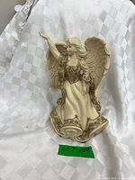 Front view of cream angel figurine music box, raised arm pose, floral gown