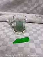 Side view of glass cylinder with candle and attached bird figure