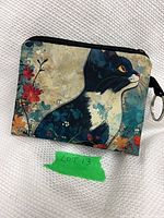 Front view of coin purse showing cat artwork, zipper, key ring
