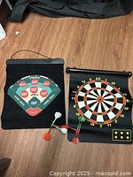 Board laid flat showing both sides and four darts