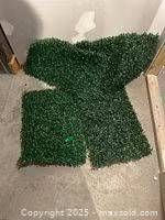 Four green plastic hedge panels laid out on floor