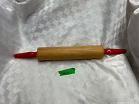 Full view of wooden rolling pin with red handles