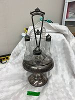 Full view of silver plated cruet stand with five glass bottles