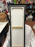 Back of framed canvas sign showing hanging wire and frame construction