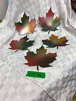 Five multicolor steel maple leaves on white cloth