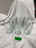 Six clear glass tumblers arranged upright on white cloth