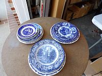 Three stacks of blue and white transferware plates on table