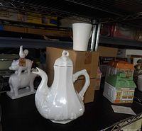 White ironstone coffee pot with lid beside white mug