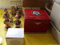 Overview showing four Goebel figurines, red Goebel ornament box, white Berta box, and glass butterfly display