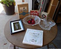 All items laid out on table including framed picture, ornament book, two glass bowls, red ornaments, SNOW and HOPE signs