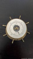 Front view of brass Airguide ship’s-wheel barometer showing dial and spokes