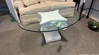 Oval glass table showing clear top and white pillar base