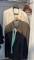 Three jackets on hangers with tie visible