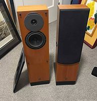 Front view of both Royd floor speakers, one grille removed showing drivers