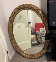 Full view of oval mirror leaning against wall