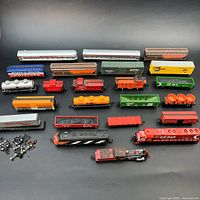 Overall view of 20 model train pieces laid out on black background