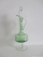 Full view of green glass decanter with clear foot, handle and stopper
