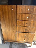 Front view of tall dresser showing cabinet door, six drawers, veneer finish, metal knobs
