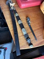 Overall view showing Japanese bayonet sword in black scabbard, Scottish dirk with ornate scabbard, and bayonet muzzle piece