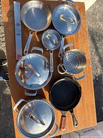 Top-down view of entire cookware set showing all stainless pots with lids, fry pan, steamer insert, cast iron skillet, magnetic bar