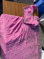Pink silk embroidered sari with matching blouse displayed on table outdoors
