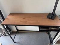Rectangular wooden desk with black metal frame visible