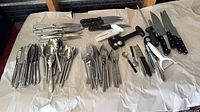 Overview of flatware, kitchen knives and utensils laid out on paper