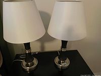 Two matching black lamps with white shades on table