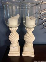 Front view of pair of hurricane candle holders showing bases and candles