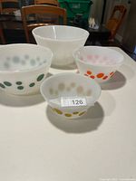 Four stacking Pyrex bowls showing gold, orange, green dot patterns and plain large bowl