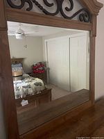Mirror with scrollwork top, reflection shows bedroom