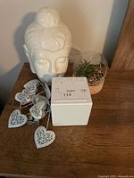 All items grouped on tabletop: Sony alarm clock, ceramic Buddha head, heart string lights, portion of succulent dome