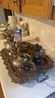 Full view of silver-plated tea and coffee pieces on ornate tray