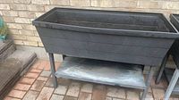 Front view of one planter showing deep planting box, legs, lower shelf with mineral stains