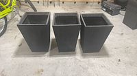 Front view of three identical tapered square planters